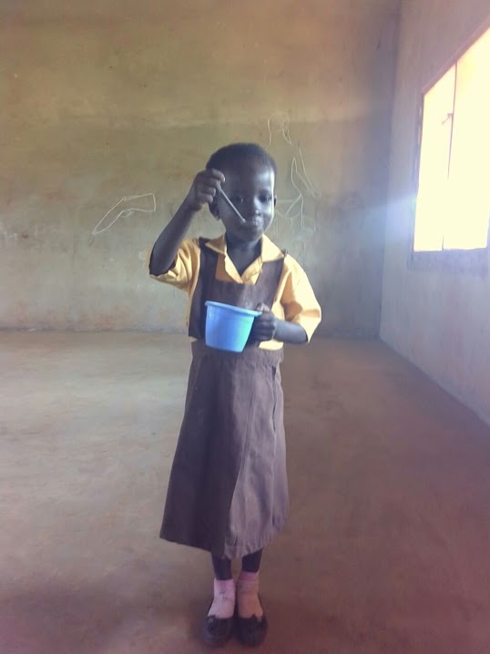 young girl stands eating porridge