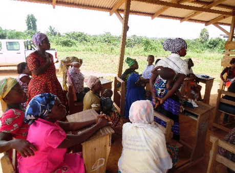 group of women gather under hut for microcredit training