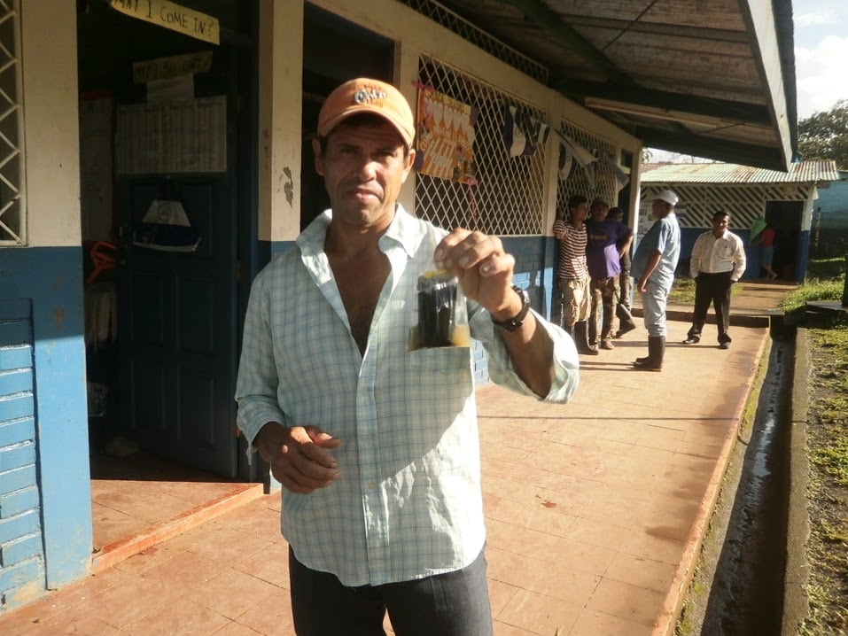 a man poses holding a sample of contaminated water