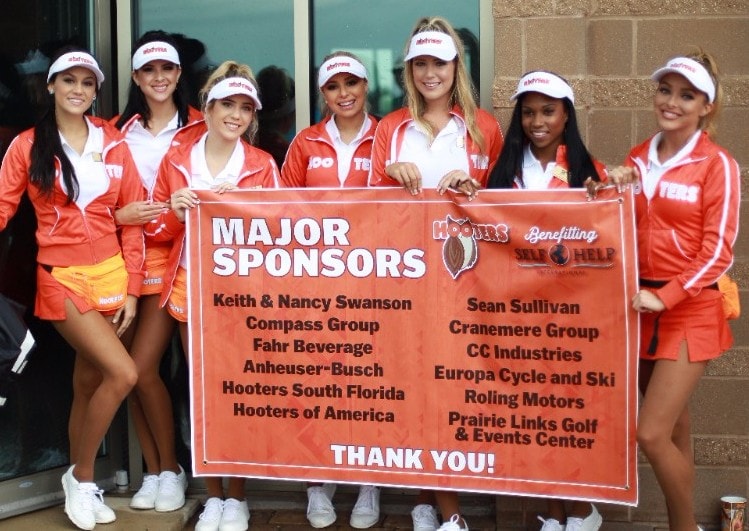 group of Hooters girls hold smile holding poster of major Self-Help sponsors