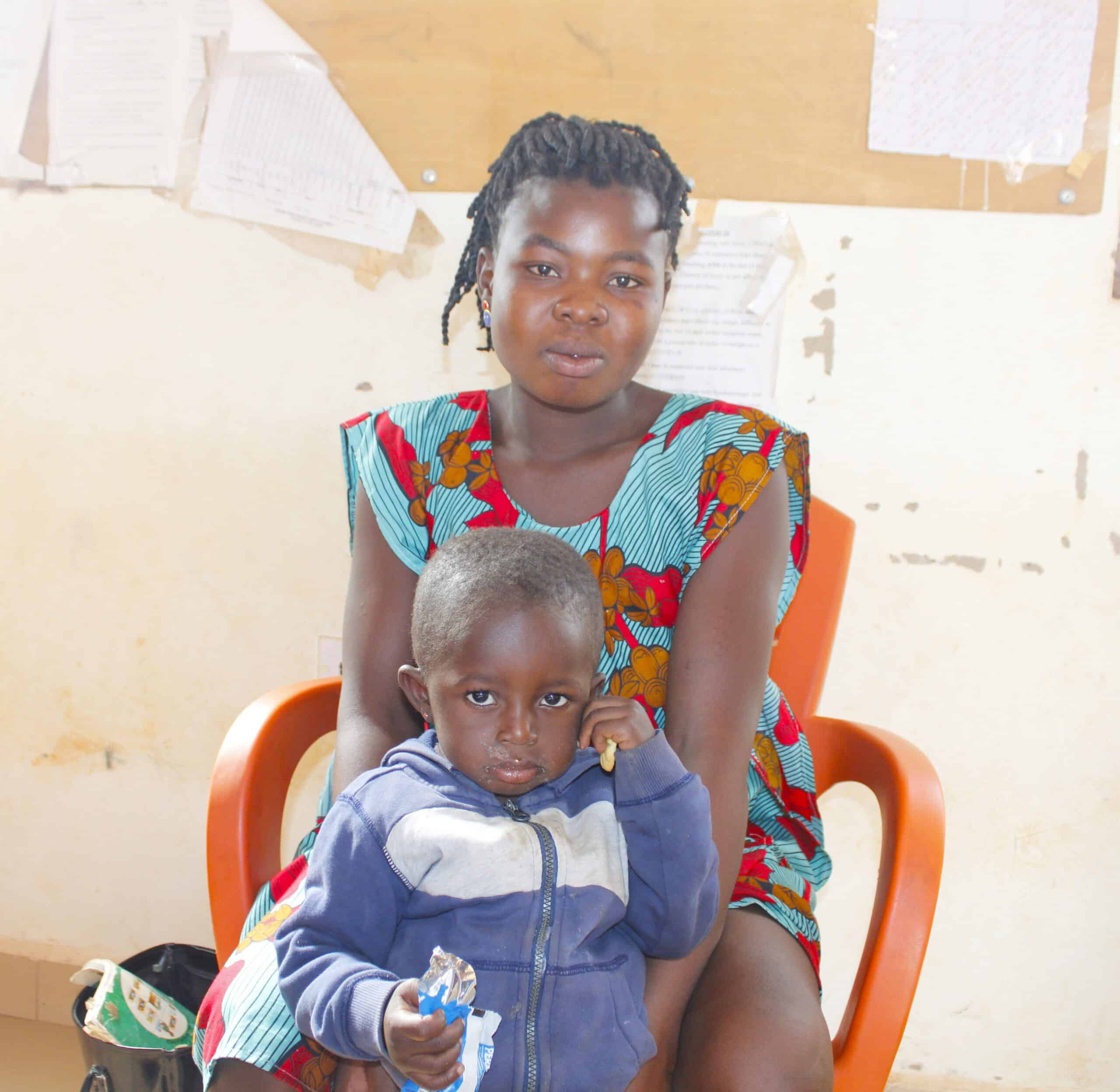 Ernestina sits in a chair with her daughter Luciana in her lap.