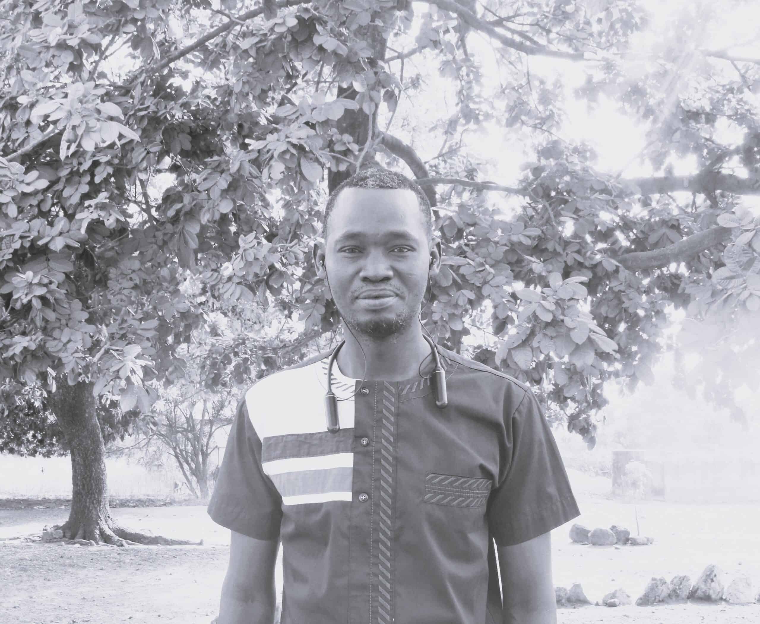 Man standing outdoors with trees in the background.