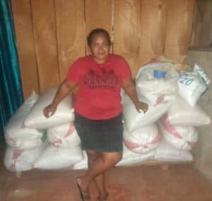Osneyda stands in front of her corn harvest.