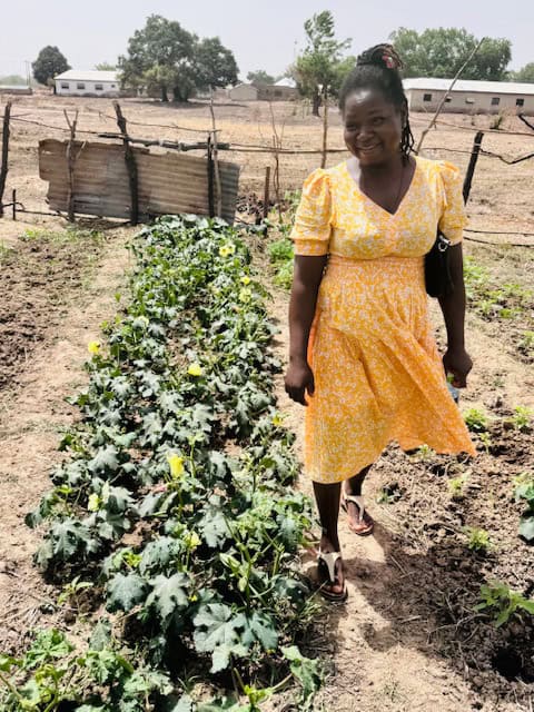 Emmaculate Etaah, Self-Help International Upper West Agriculture Programs Officer, stands in a garden at the Dantie Dam demonstration plot.